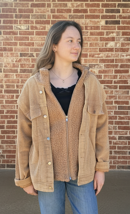 Person wearing a tan corduroy sherpa jacket with a brick wall background
