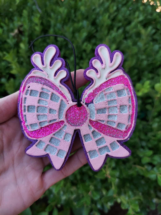 Disco bow with antlers held in a hand with a green outdoor background