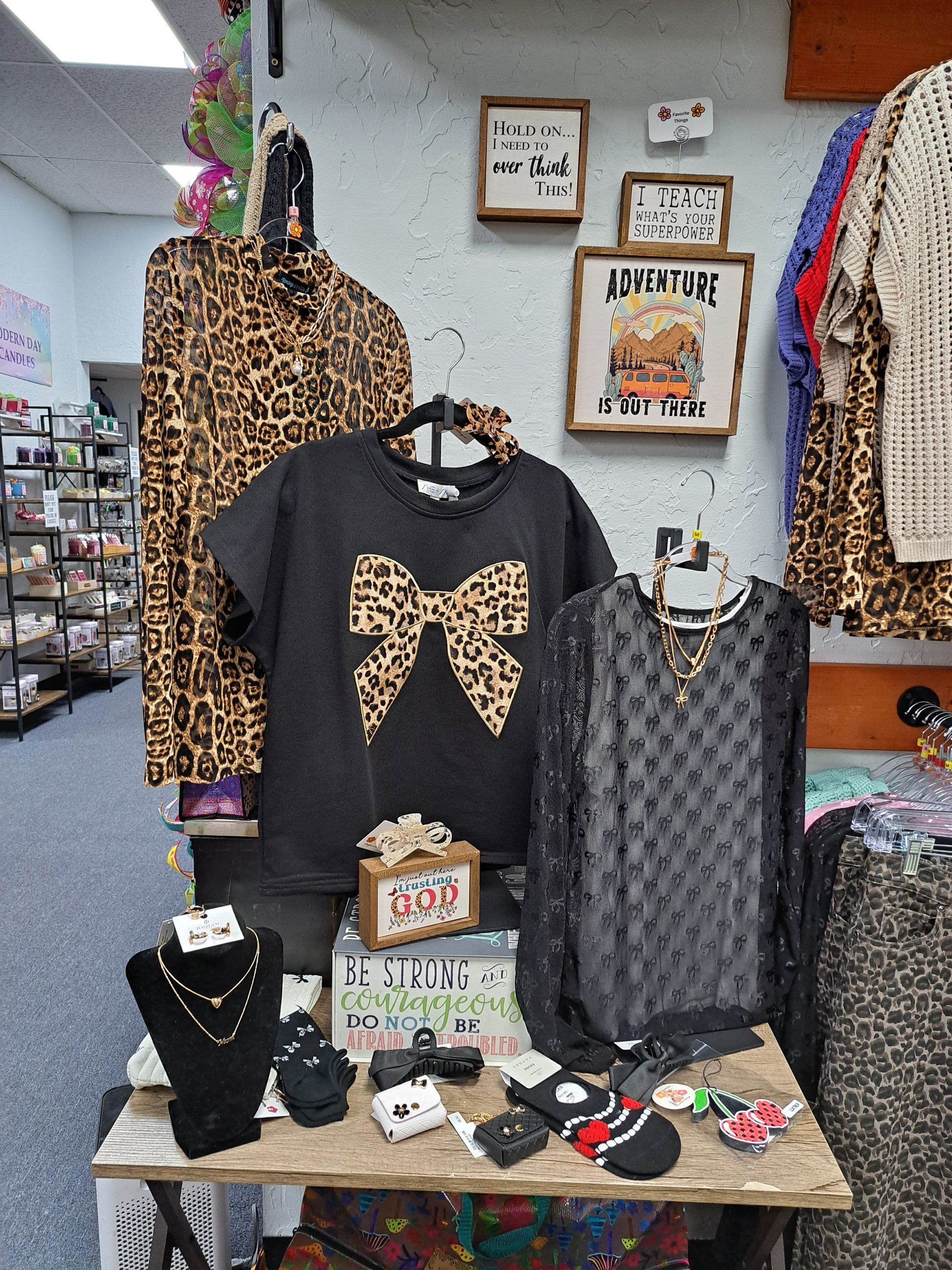 store display of 3 leopard print and black tops on a table, white background