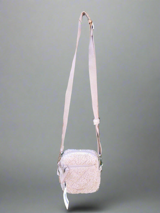 Beige crossbody bag with a strap on a neutral background