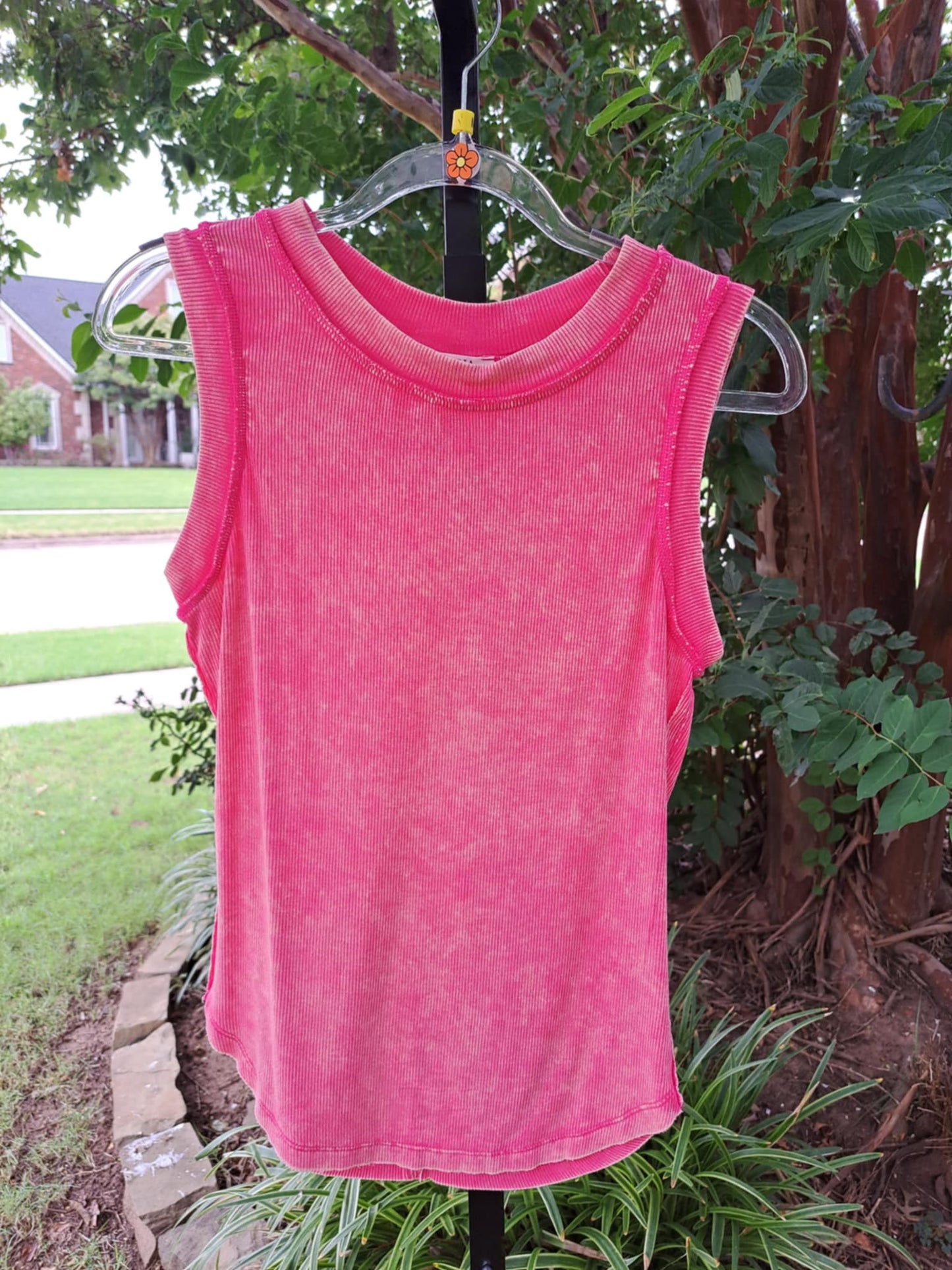 Pink sleeveless top on a hanger against a natural background