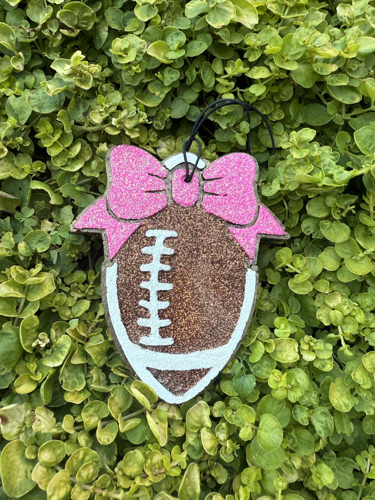 football air freshener on string with pink bow. Greenery background
