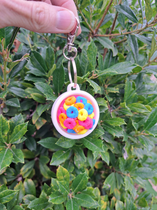 Keychain with colorful cereal loops held in front of green foliage