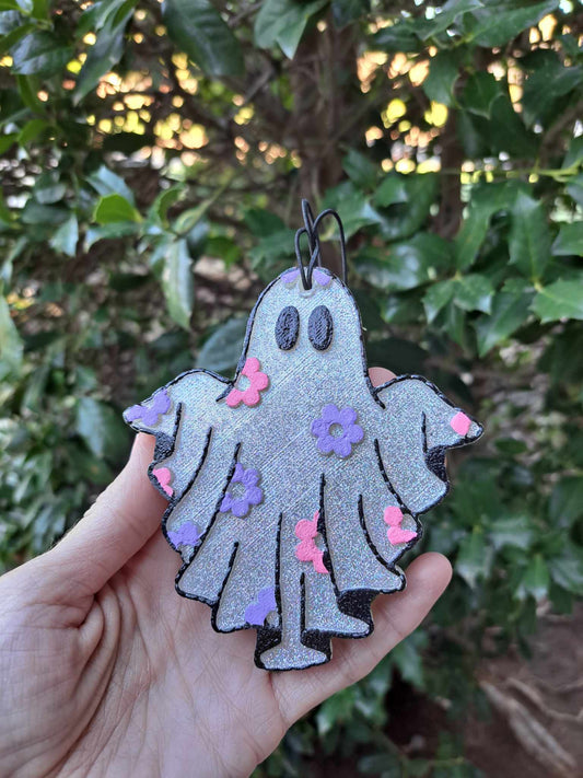 halographic ghost air freshener with daisies on front held in front of foilage