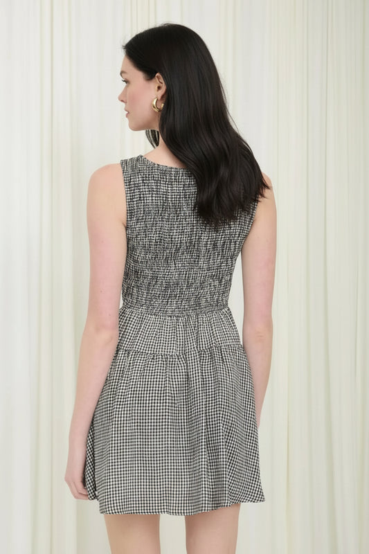 Woman wearing a black and white checkered dress against a white curtain background