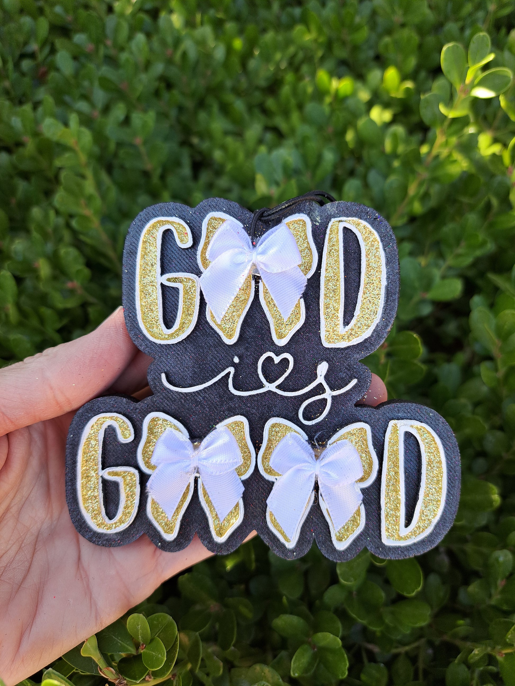 God is good air freshener with bows in front of greenery background