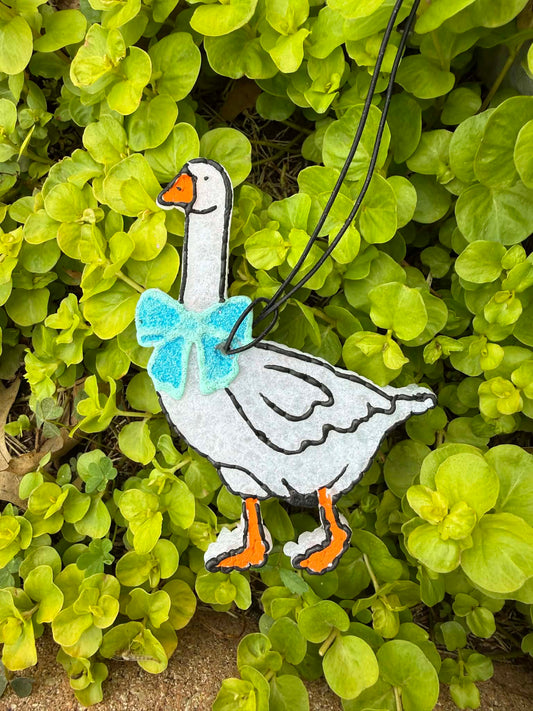 Decorative goose freshie with a blue bow on a green leafy background