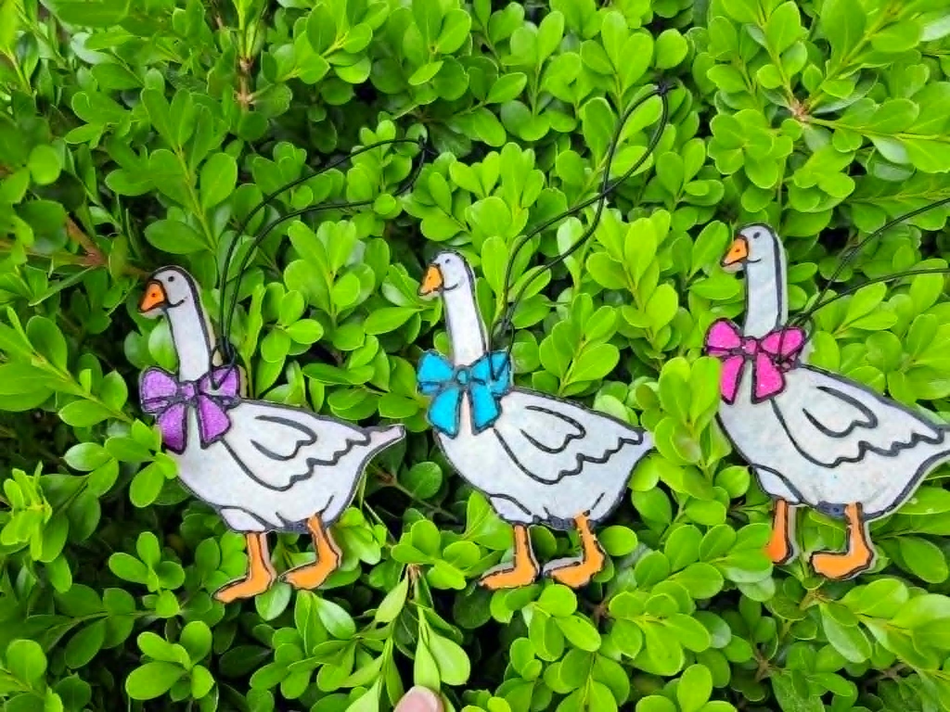 goose freshies with bows in front of leafy background