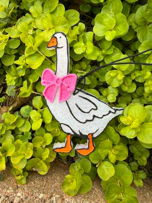 Decorative goose freshie with a pink bow on green leaves