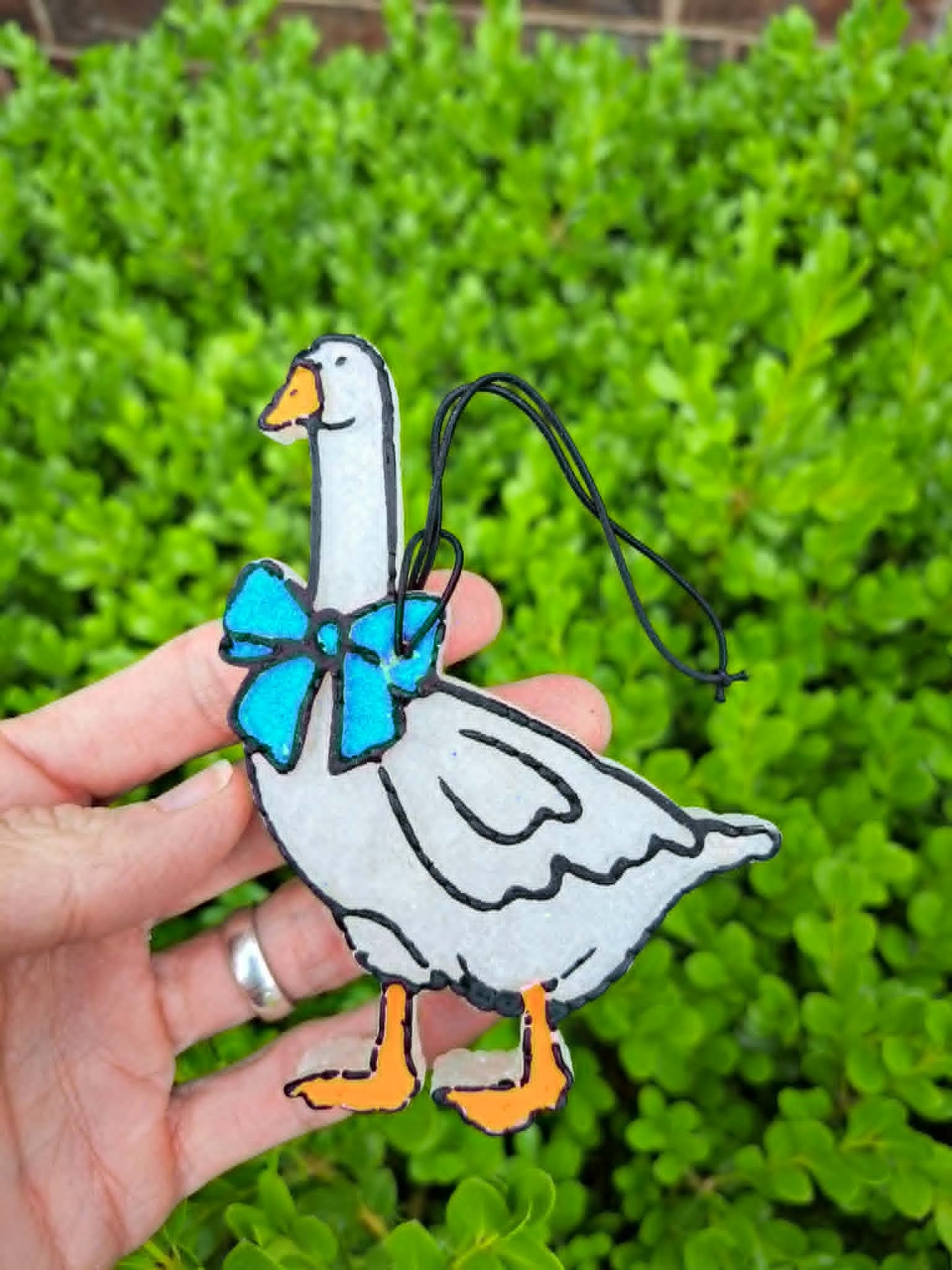 goose with blue bow held in front of leafy background