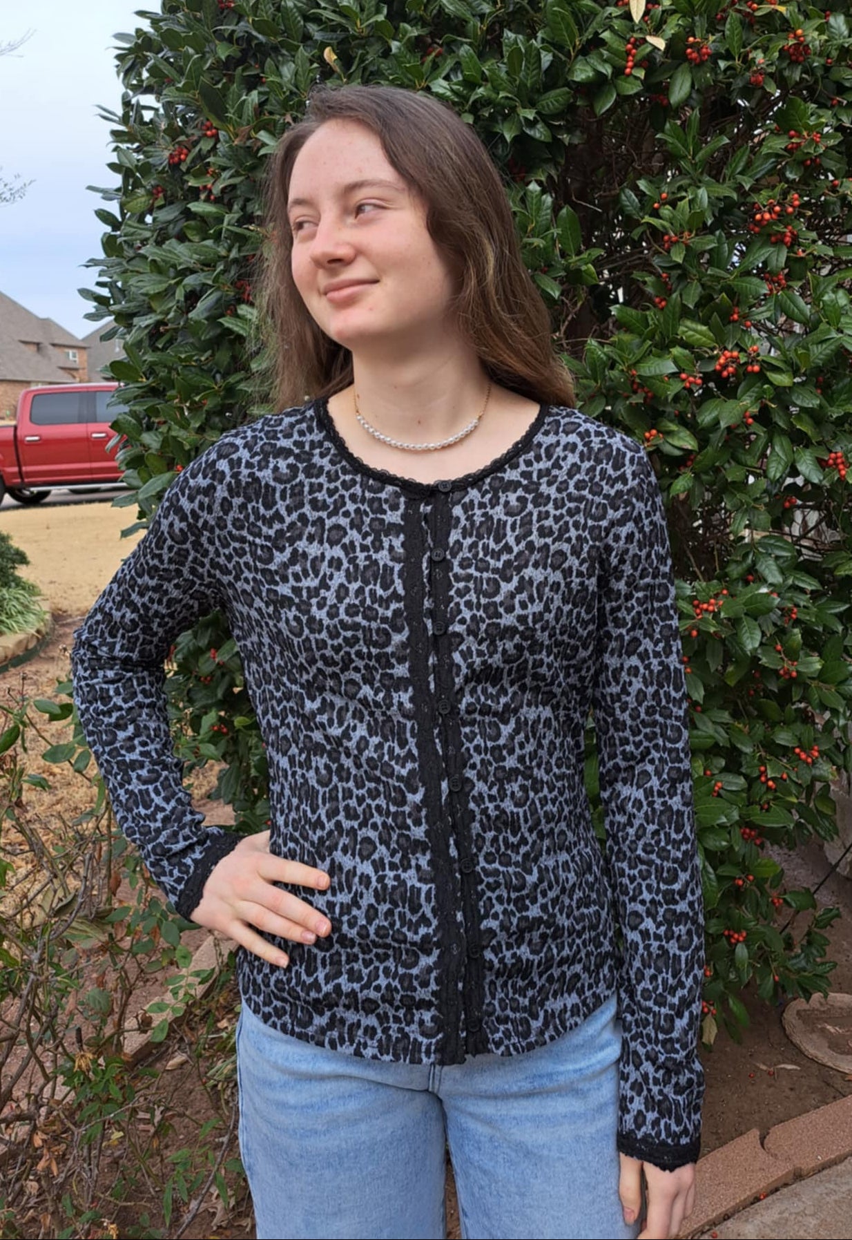 woman wearing gray leopard top in front of greenery