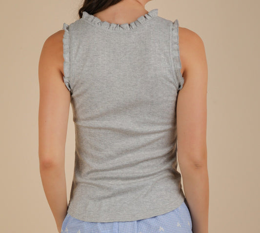 Woman wearing a gray sleeveless top with ruffled shoulders against a beige background