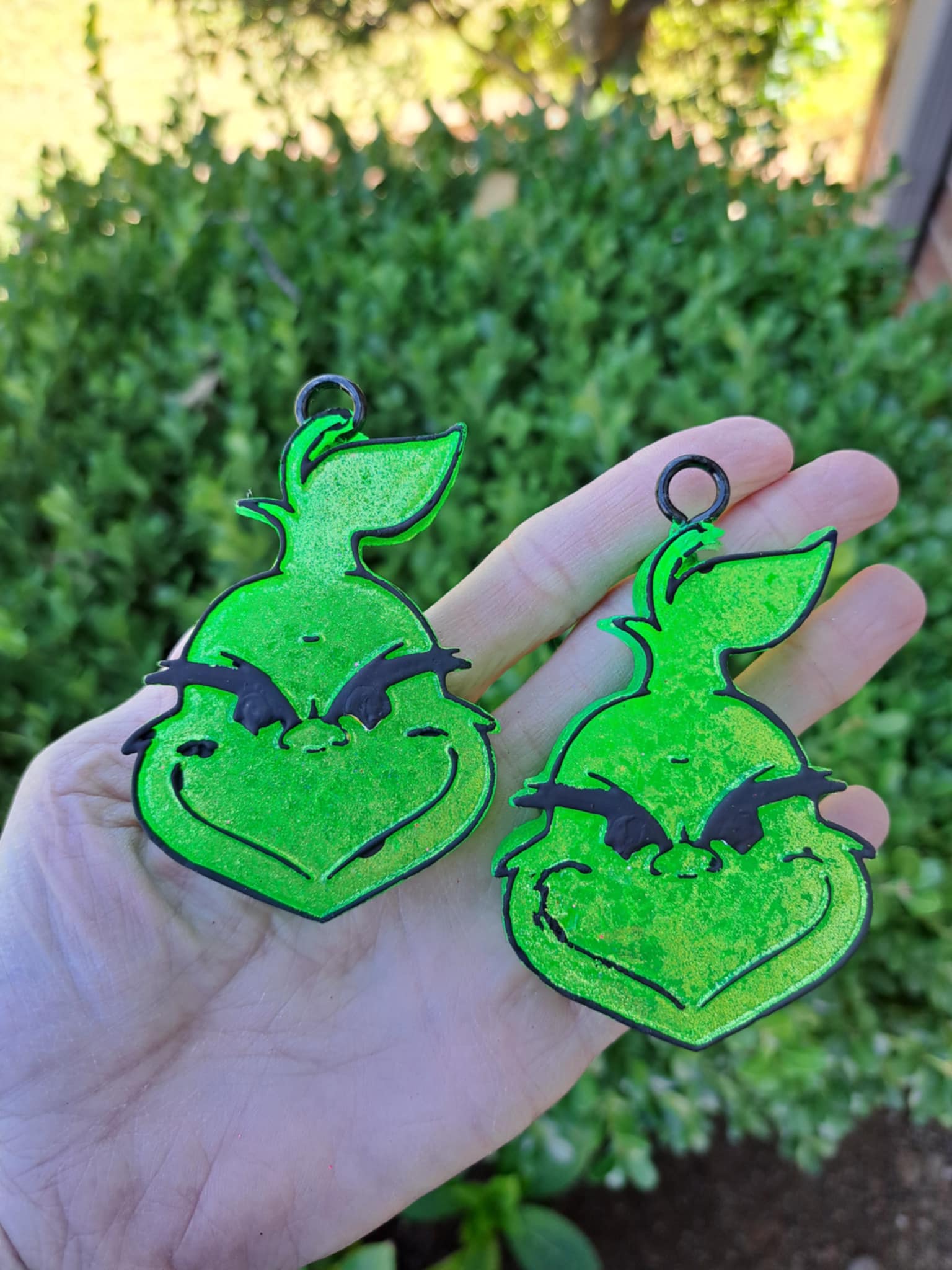 Green guy face vent clips held by hand in front of greenery