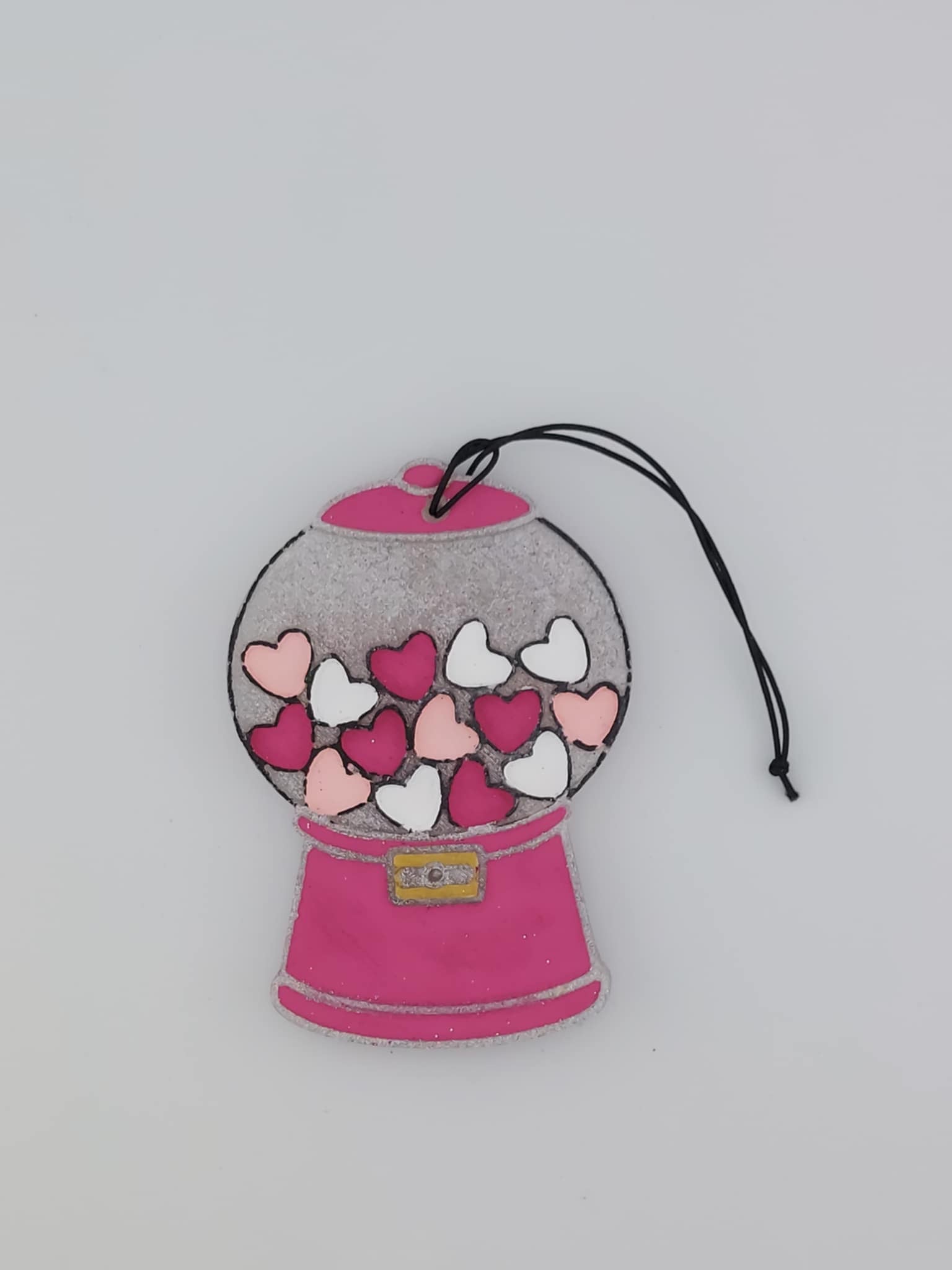 A handmade air freshener shaped like a pink gumball machine with heart-shaped gumballs inside, hanging by a black elastic string.