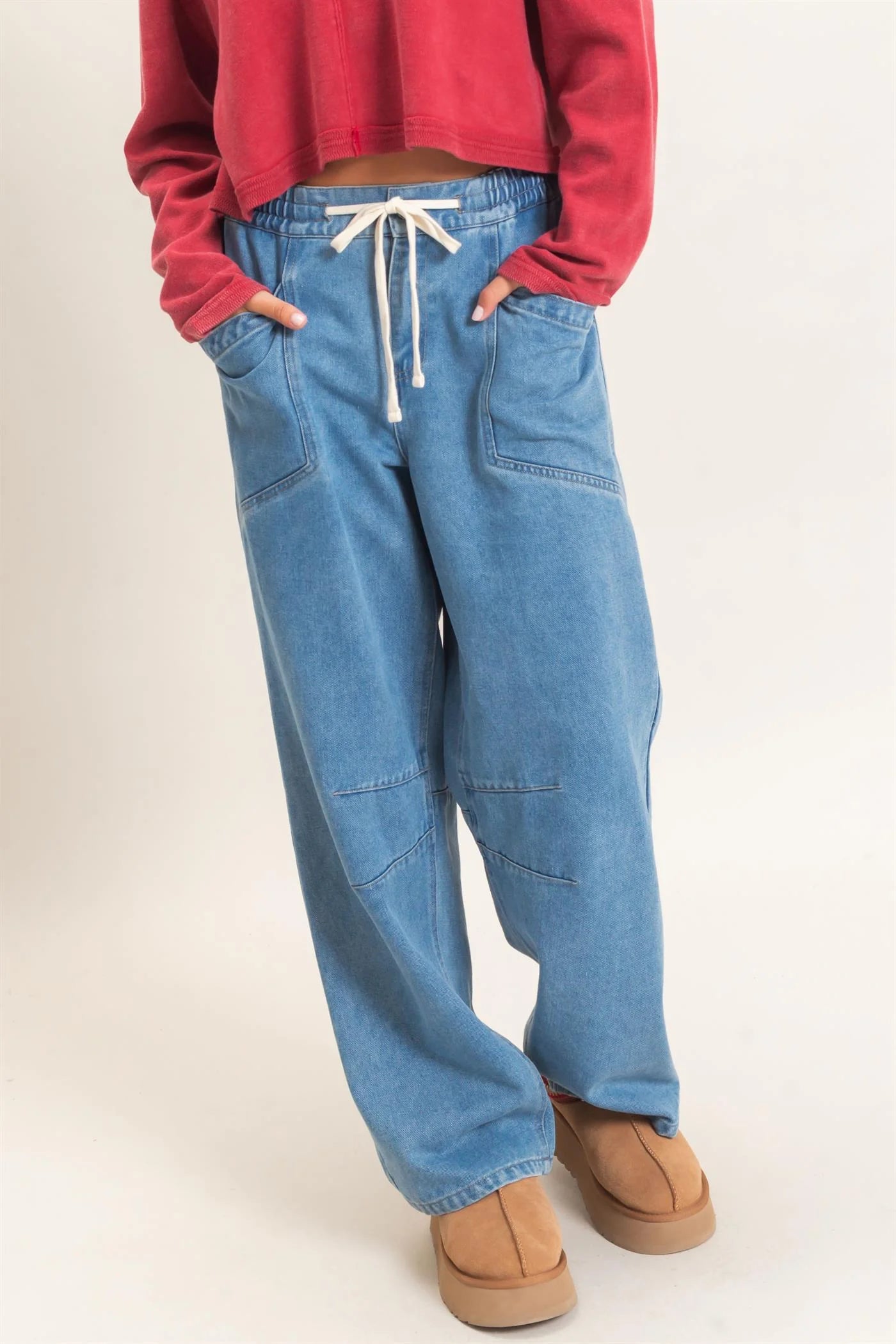Person wearing blue jeans with a red top on a white background