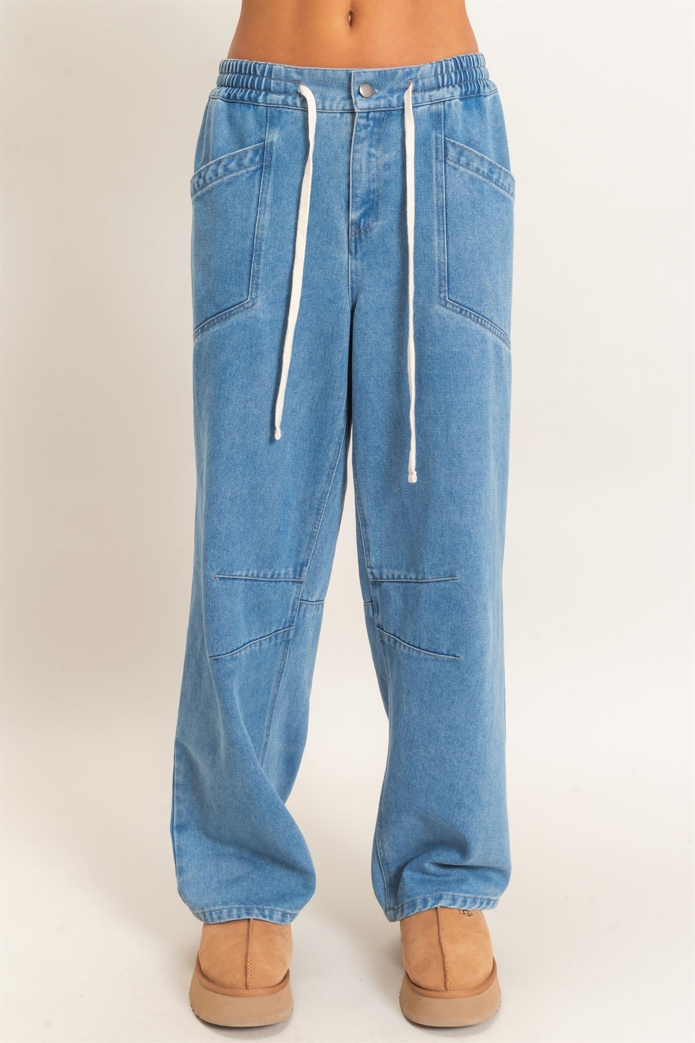 Blue jeans with a white drawstring on a beige background