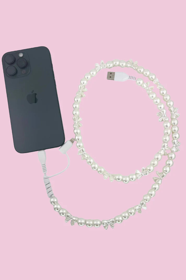 Black phone with a pearl USB phone charger on a pink background