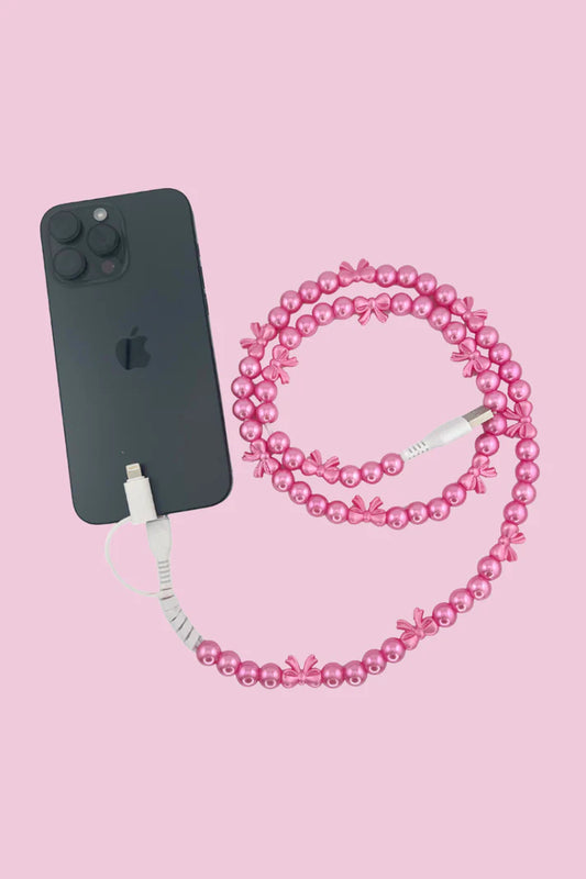 Black phone with pink beaded phone charger cable on a pink background