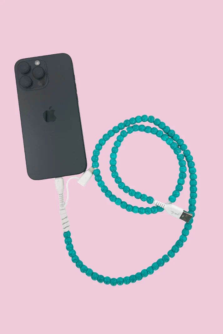 Black phone with teal beaded 2 in 1 phone charger cable on a pink background