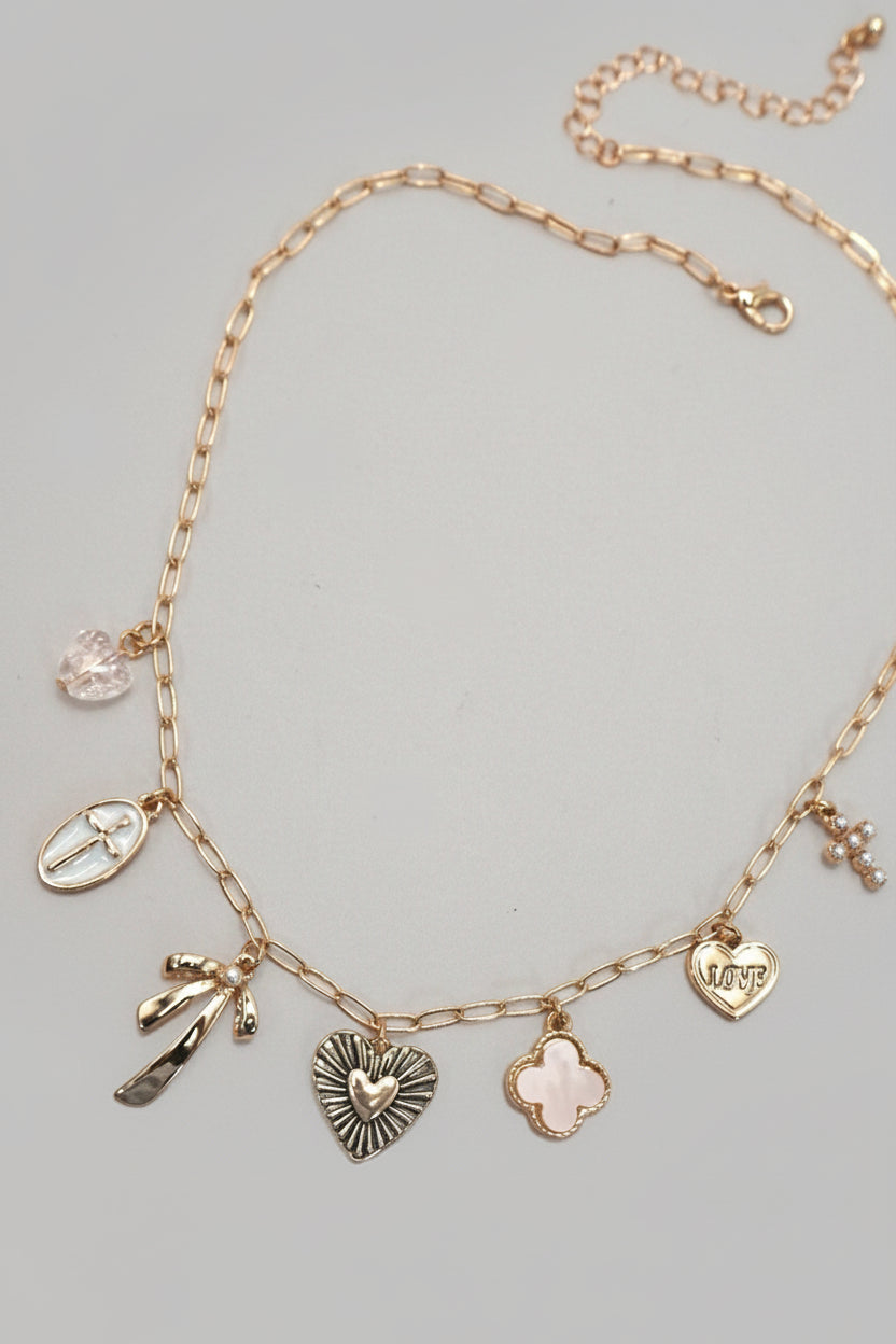 Gold necklace with various charms on a neutral background