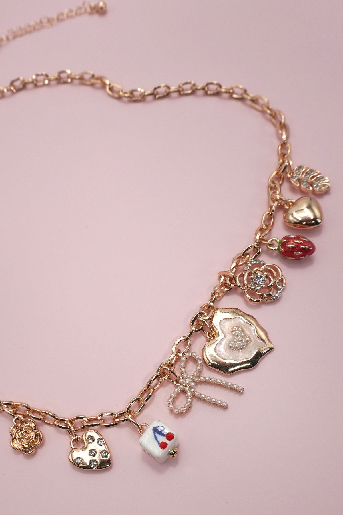 Necklace with various charms on a pink background