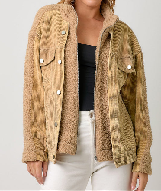 Woman wearing a beige sherpa jacket on a plain background