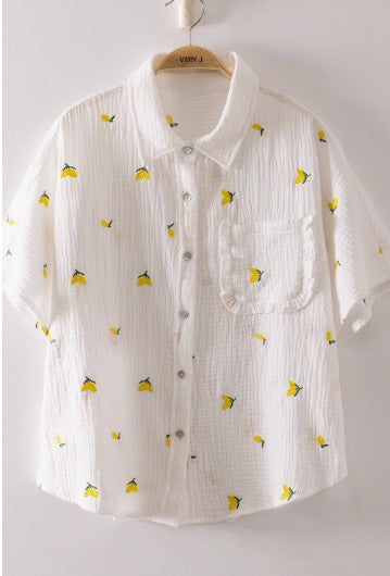 White shirt with lemon pattern on a hanger against a white background