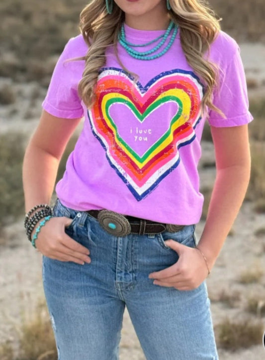 Woman wearing a pink t-shirt with a colorful heart design outdoors. Front view.