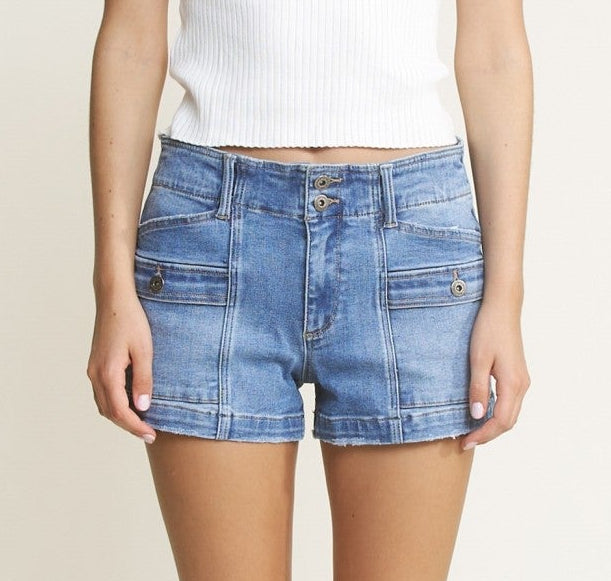 Woman wearing a white t-shirt and blue denim shorts on a plain background