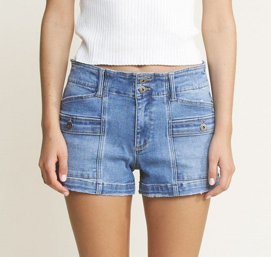 Woman wearing a white t-shirt and blue denim shorts on a plain background