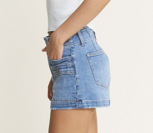 Woman wearing a white t-shirt and denim shorts on a plain background