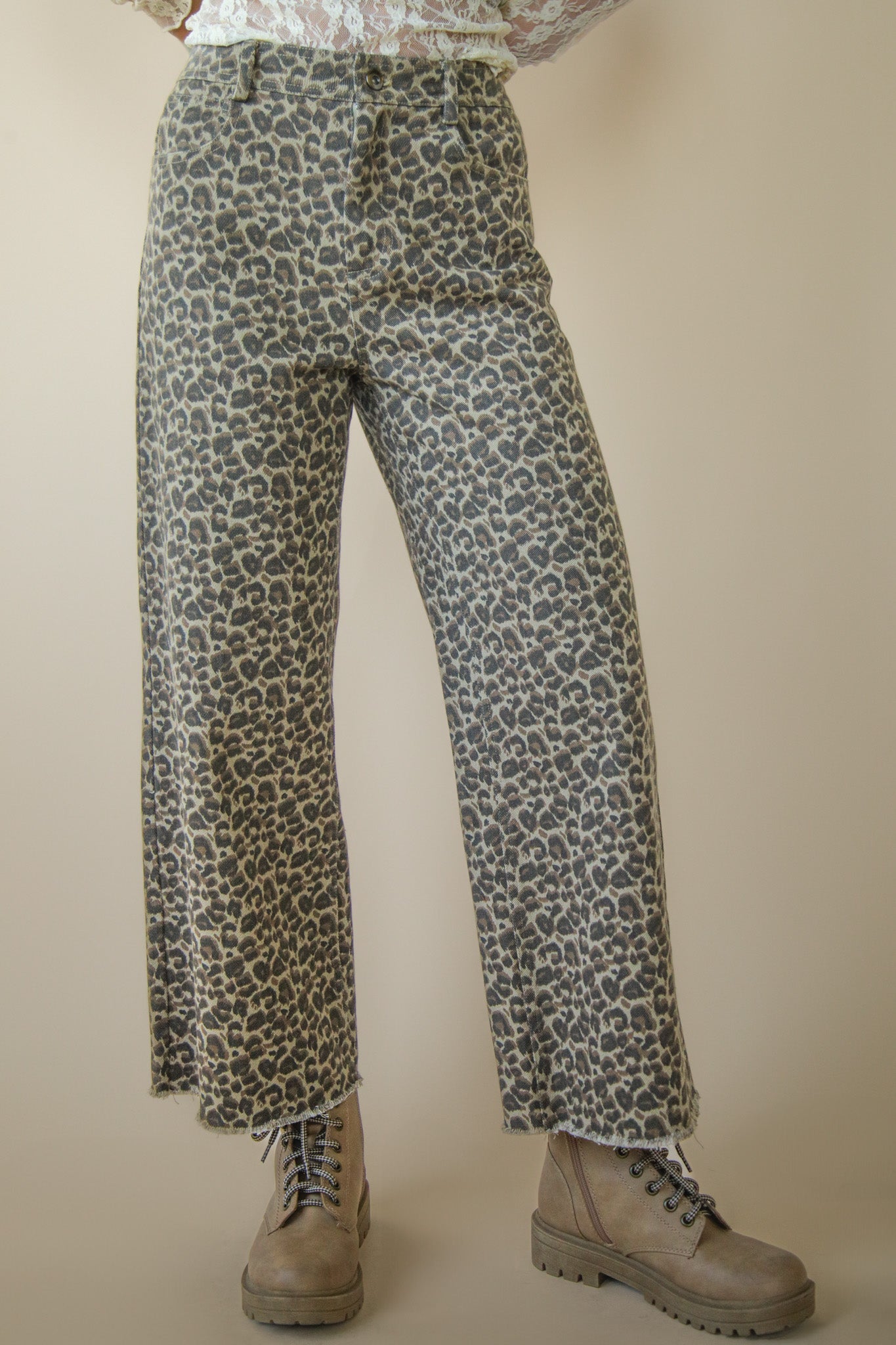 Leopard print pants worn with beige boots on a plain background