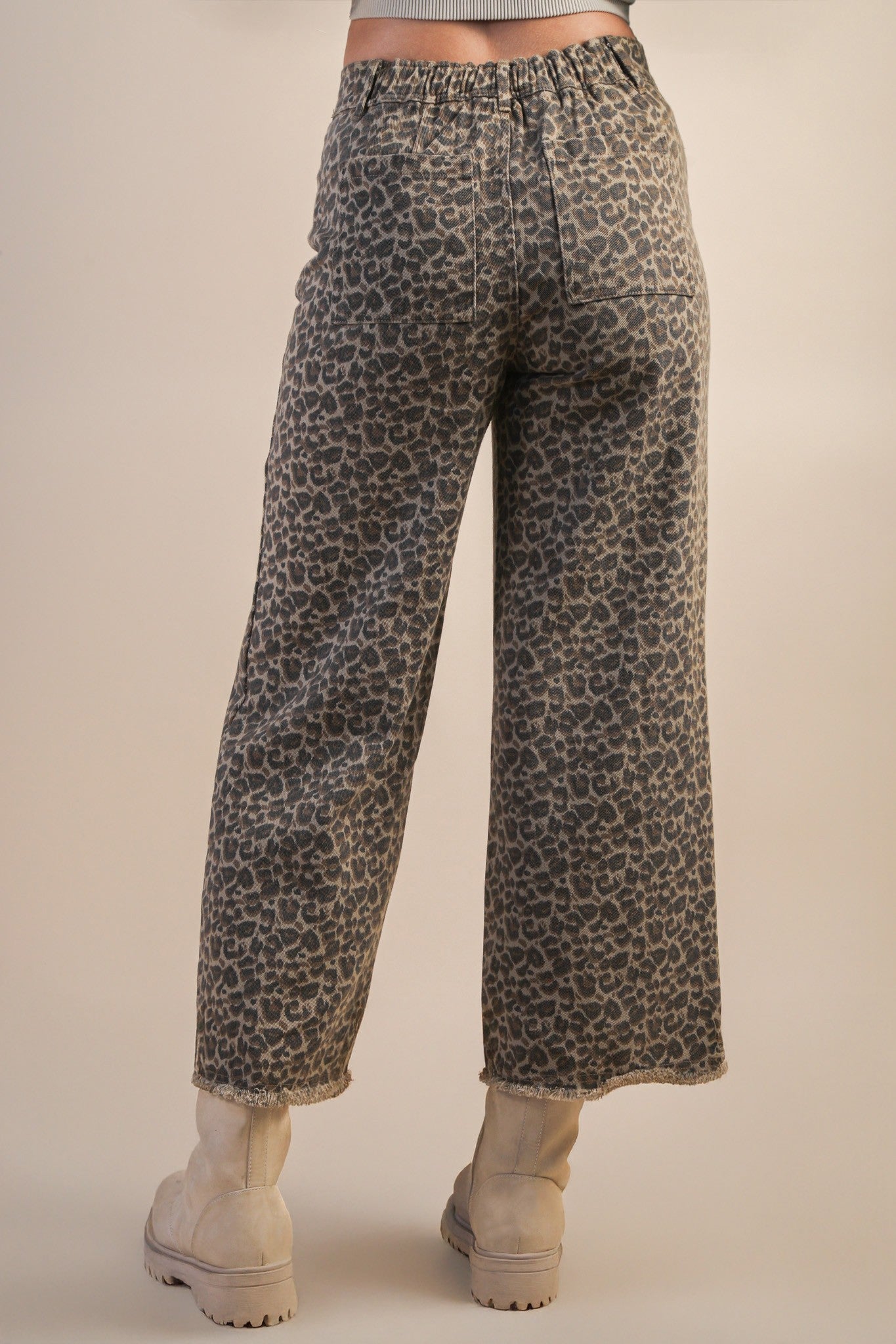 back view of model wearing mocha leopard jeans and boots on beige background