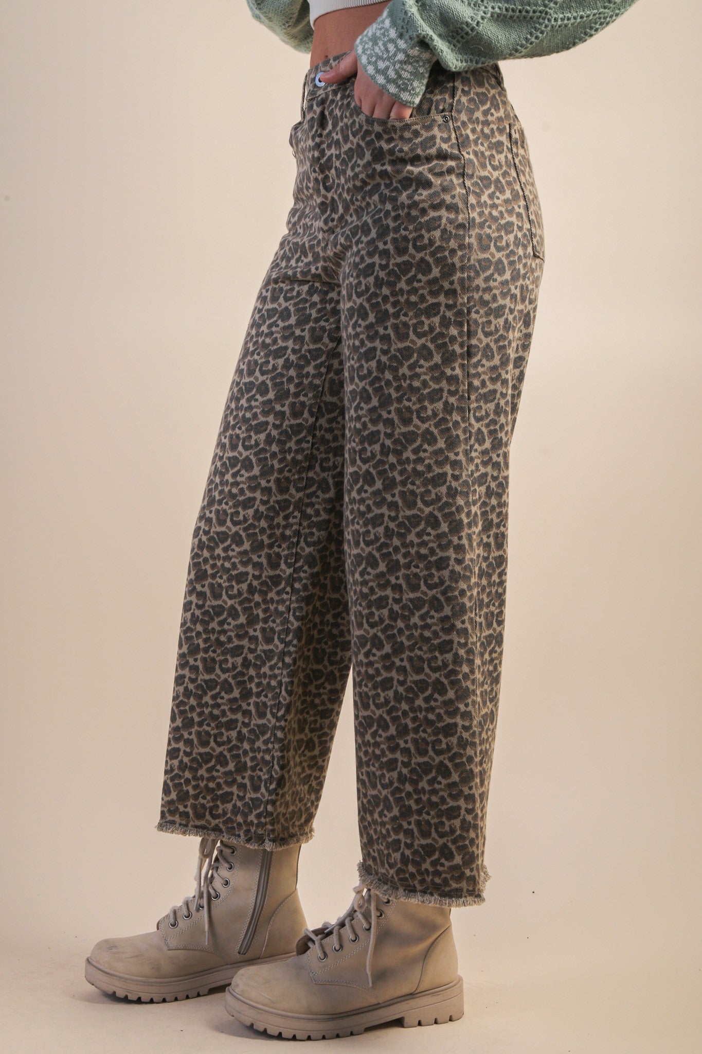 side view of person wearing leopard jeans and boots. Beige background