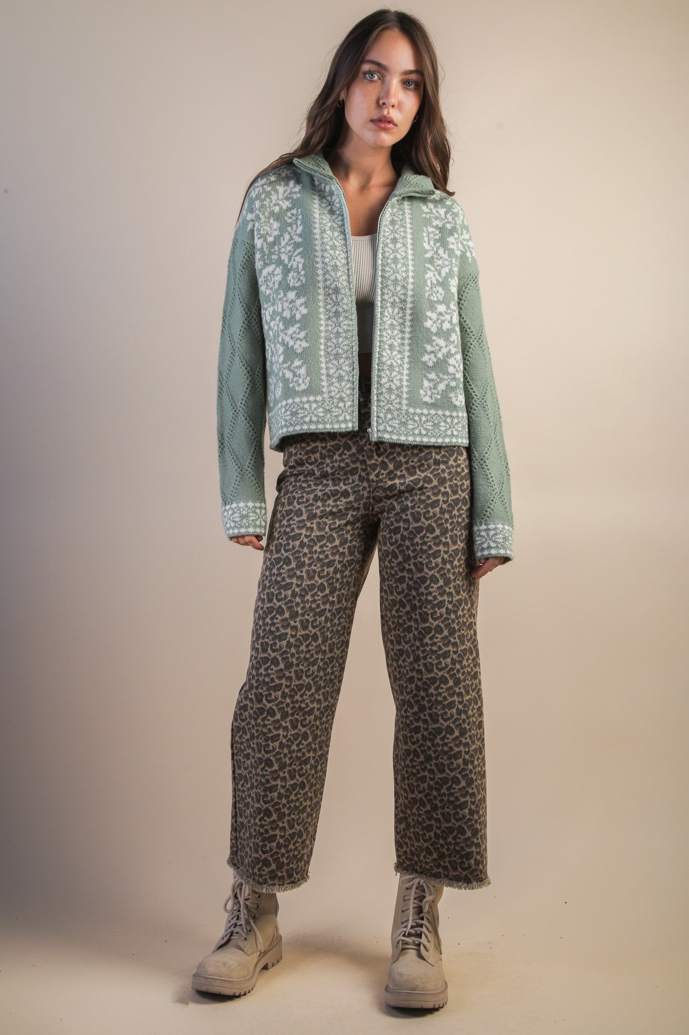 person wearing sweater and mocha leopard jeans on a beige background