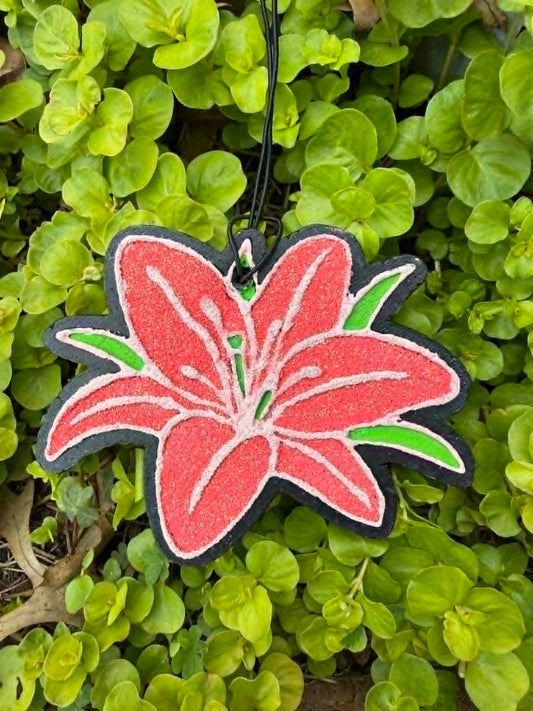 Decorative orange flower freshie hanging among green leaves