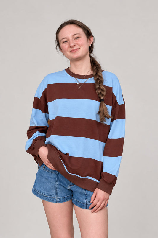 woman wearing a blue and brown oversized stripe knit top and denim shorts