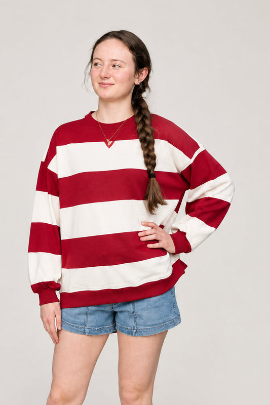 woman wearing a red and white oversized stripe knit top against a neutral background