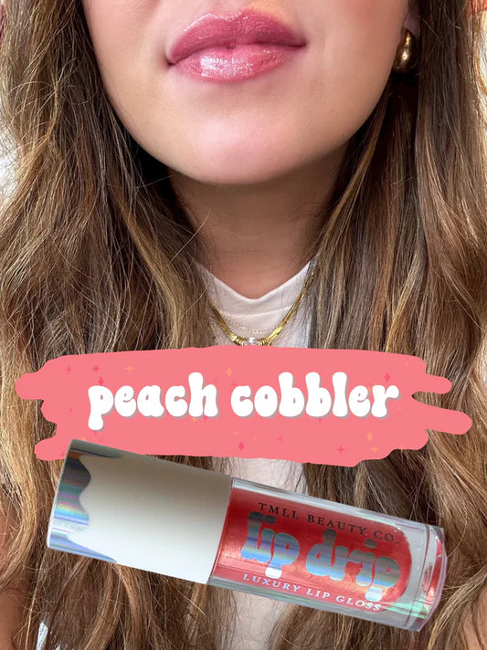 Close-up of a person wearing pink lipstick with a lip gloss labeled 'peach cobbler' in the foreground.