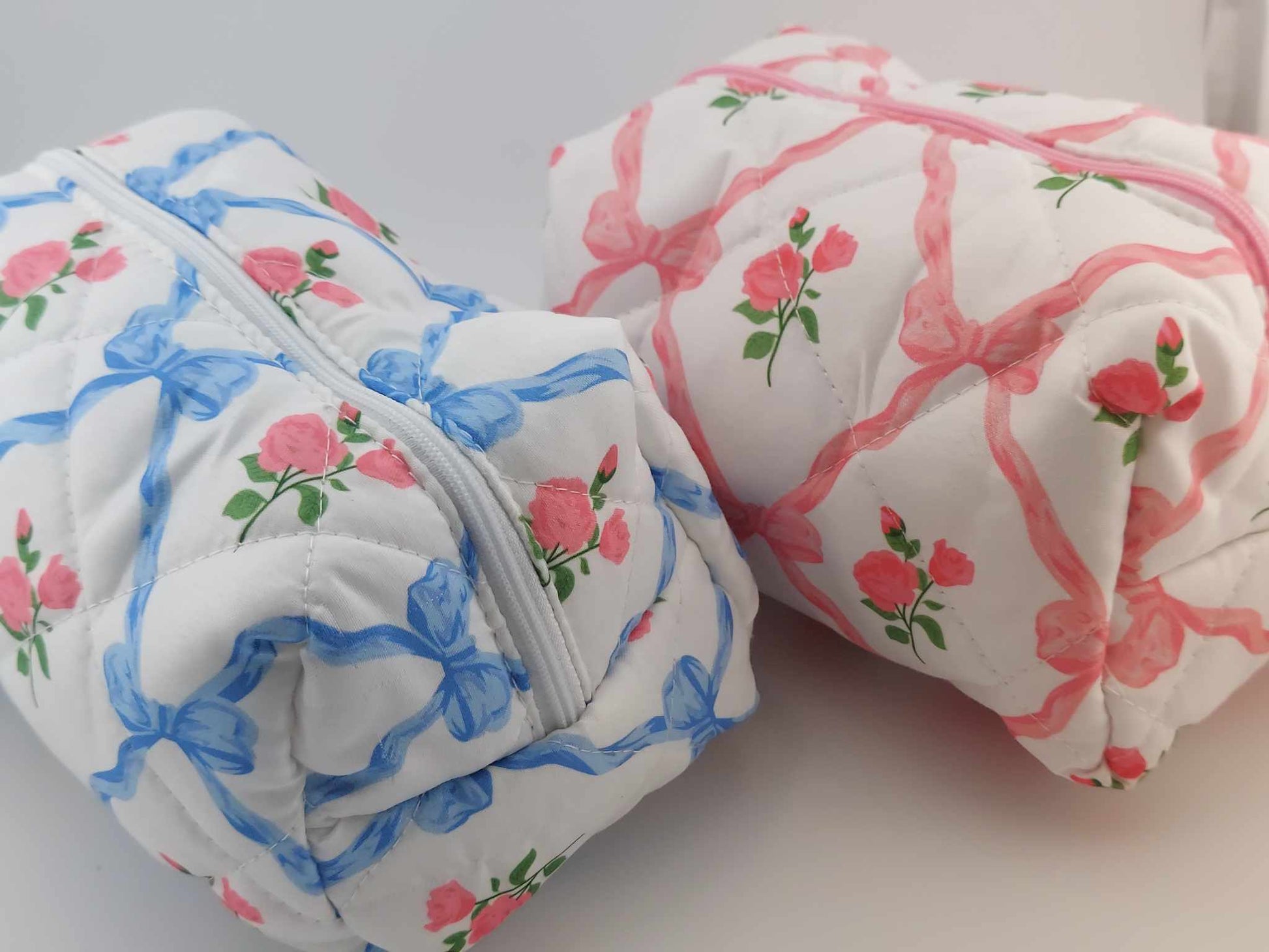 cosmetic bags with pink and blue bows and pink roses on a neutral background
