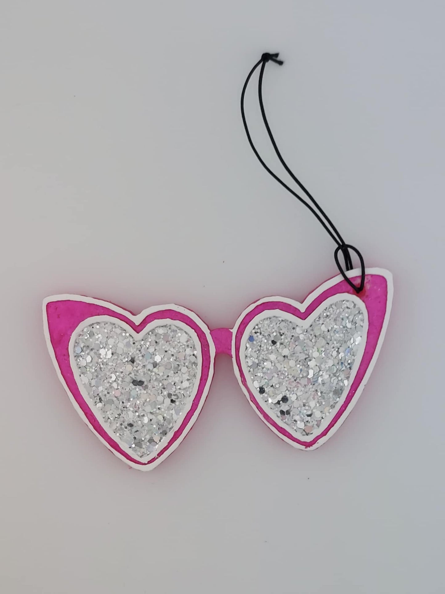 A pair of heart-shaped glitter air freshener with black elastic string.