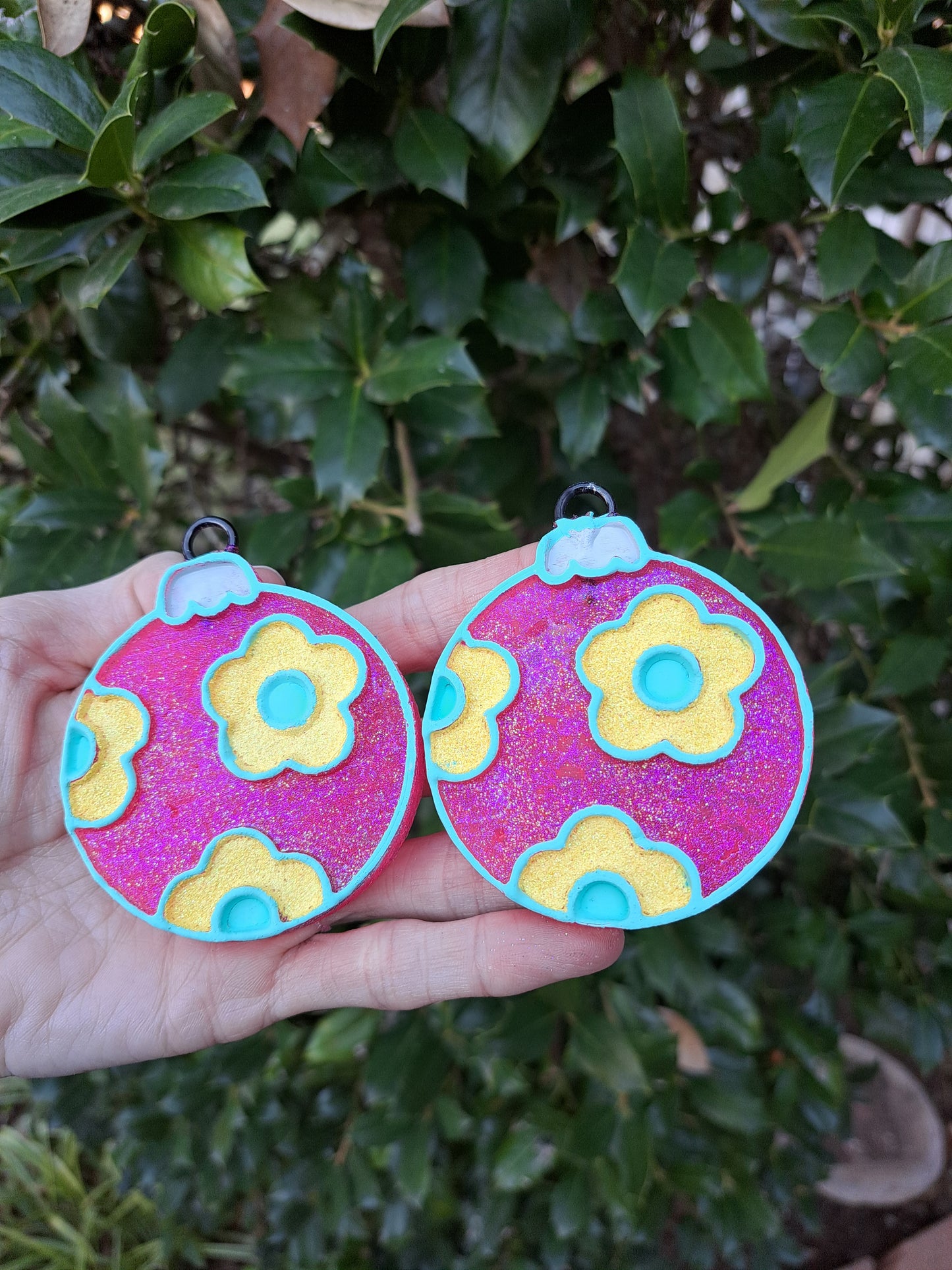 pink Christmas bulb vent clips in hand in front of greenery