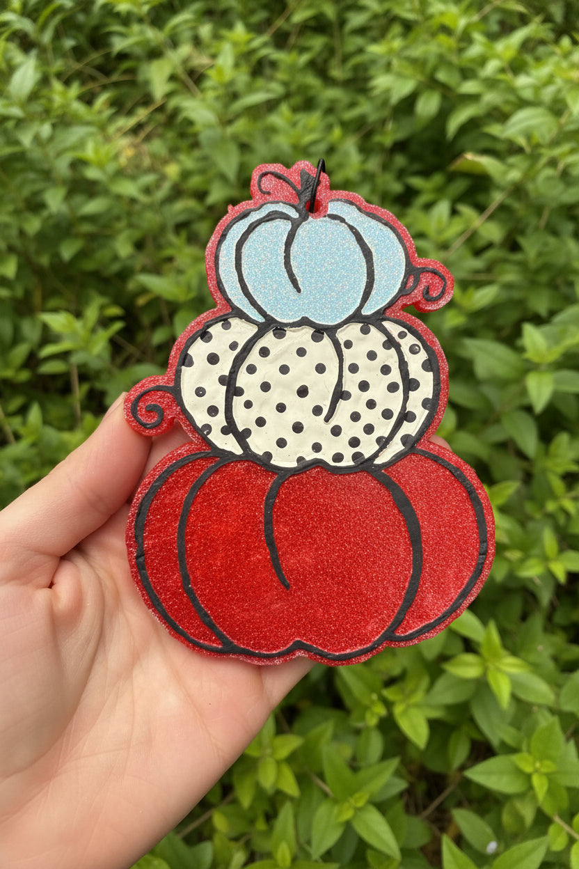 hand holding a pumpkin shaped freshie with polka dots against a leafy background