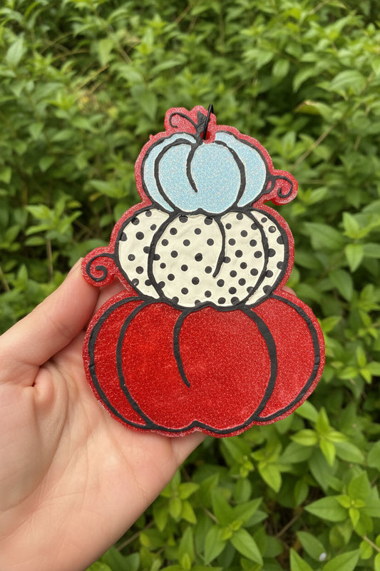 hand holding a pumpkin shaped freshie with polka dots against a leafy background