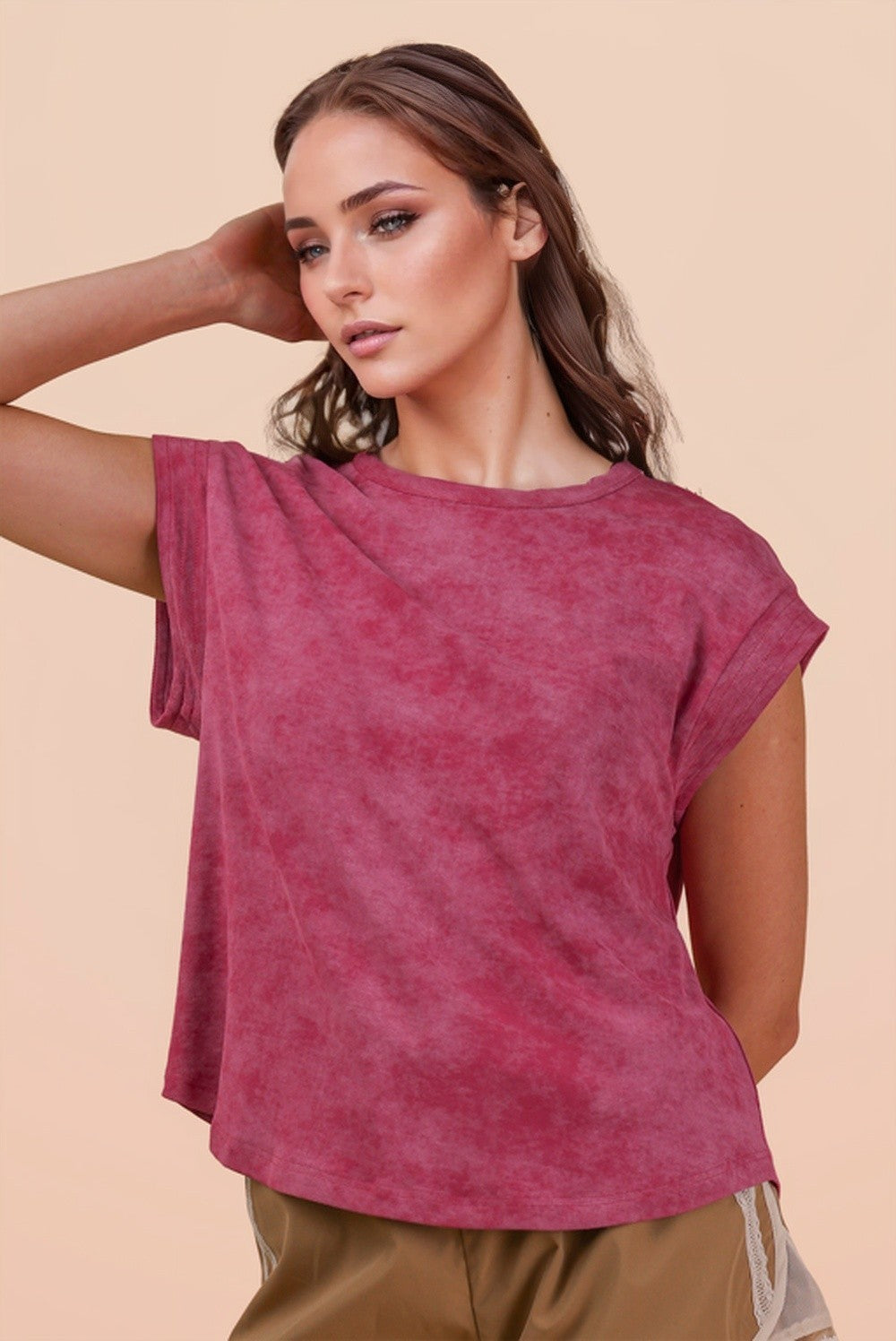 Woman wearing a maroon t-shirt against a beige background