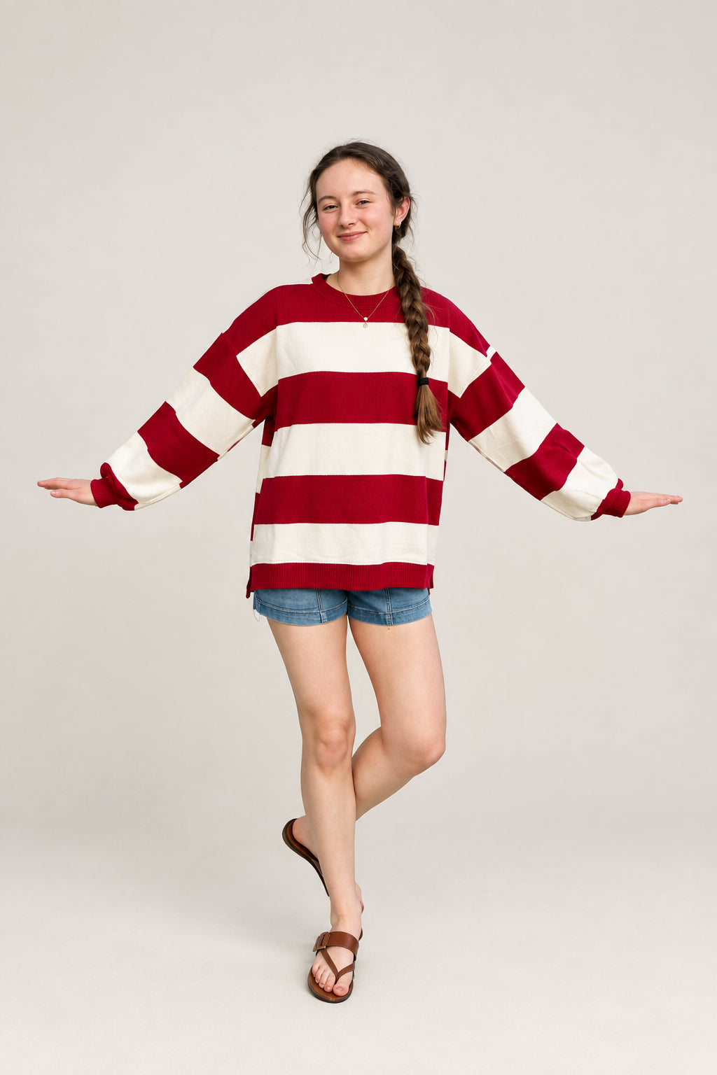 woman wearing a red and white oversized stripe knit top and denim shorts