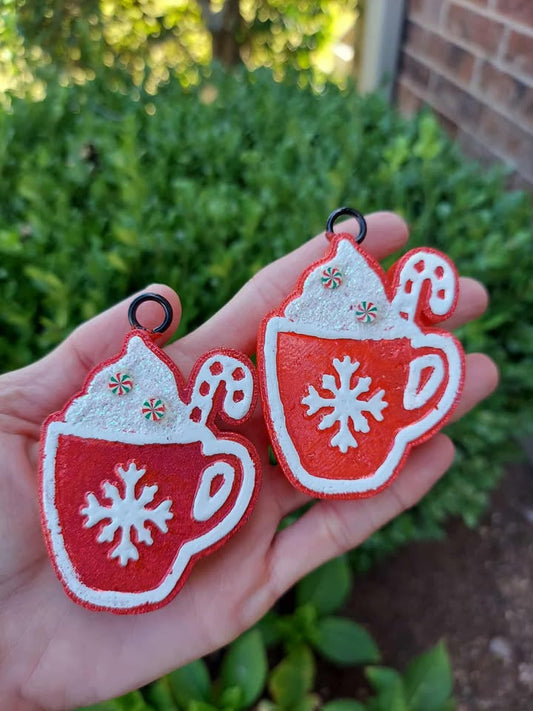 Red and white Christmas-themed mug  vent clips held in a hand with greenery in the background