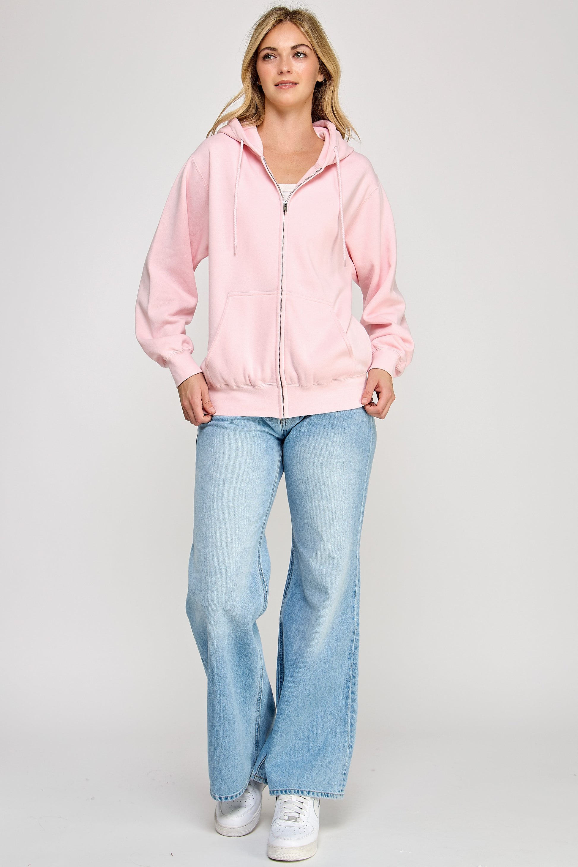 Woman wearing a pink jacket and light blue jeans on a white background