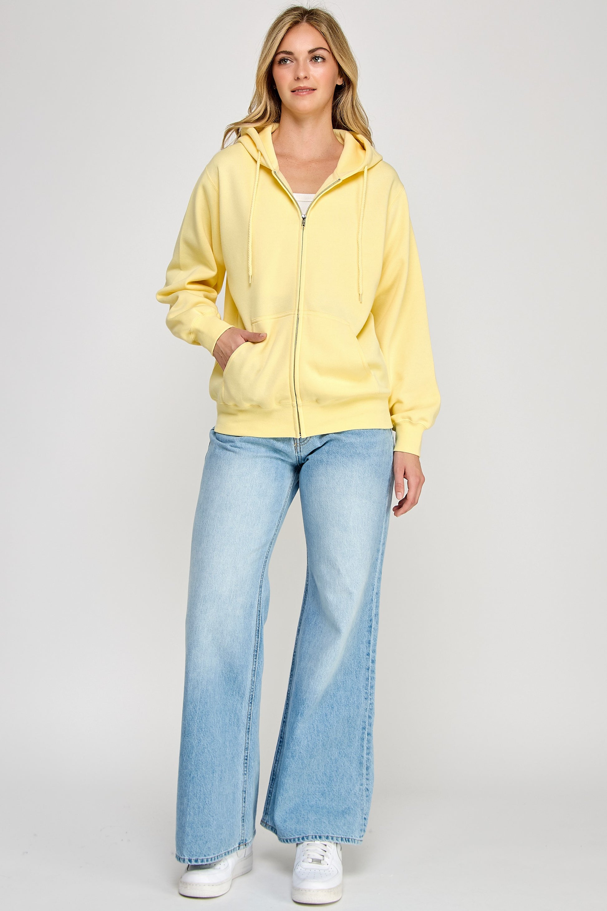 Woman wearing a yellow jacket and blue jeans on a white background