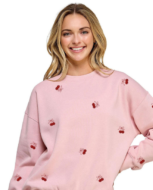 Woman wearing a pink sweatshirt with small red cherries on a white background